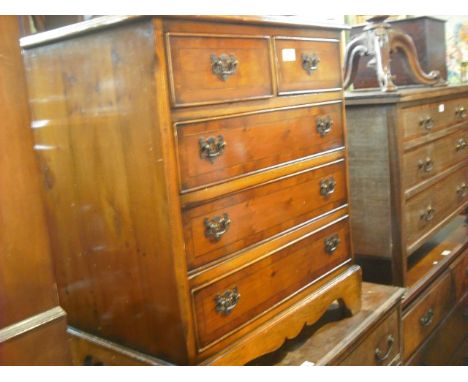 A reproduction yew wood veneered and crossbanded chest of small proportions, the rectangular top with moulded edge over two s