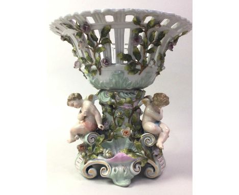 GERMAN PORCELAIN TABLE CENTREPIECE, LATE 19TH CENTURY  the pierced circular basket modelled above three winged cherubs seated