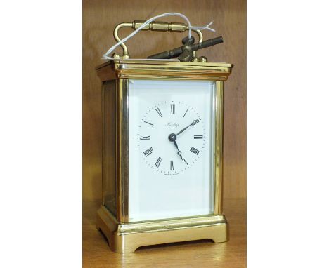 A brass carriage clock, the white enamel dial with Roman numerals, marked 'Henley, Made in England'. to a plain case with han