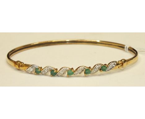 A 9ct gold bangle set five round-cut emeralds with diamond points between, 4.6g, cased.