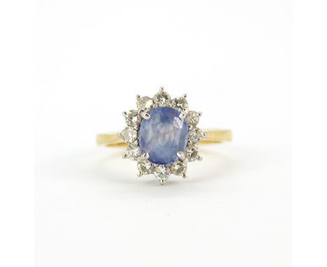 An 18ct yellow gold cluster ring set with an oval cut Ceylon sapphire surrounded by diamonds, (K).