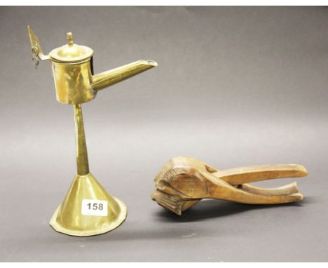 An early brass oil lamp, H. 30cm, together with a carved wooden dog nutcracker with glass eyes.