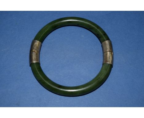 A dark jadeite hinged bangle having metal mounts.