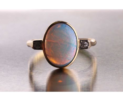 An opal and diamond ring, consisting of an oval cabochon opal measuring approximately 12.9 x 9.8 mm, rub over set on a yellow