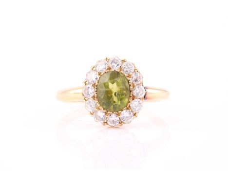 An 18ct gold peridot and diamond entourage ring, consisting of an oval peridot measured approximately 7.9 x 5.9 mm, rub over 