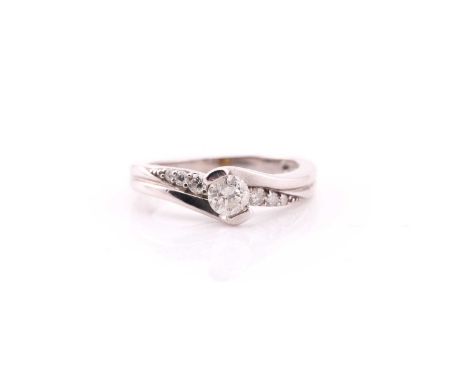 A single stone diamond ring; the round brilliant cut diamond in 9ct white gold crossover mount with three stone graduated rou