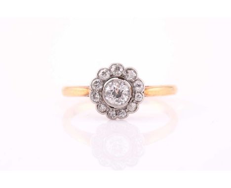 A yellow metal and diamond daisy-cluster ring, millegrain set to center with an old round-cut diamond of approximately 0.20 c