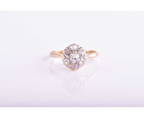 A seven stone diamond cluster ring; the mixed old cut diamonds in claw mounts to a pierced gallery and plain shank marked '18