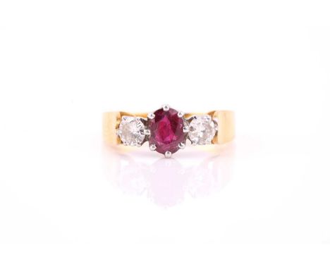 A ruby and diamond three stone half hoop ring; the oval cut ruby in eight claw mount and flanked with round brilliant cut dia
