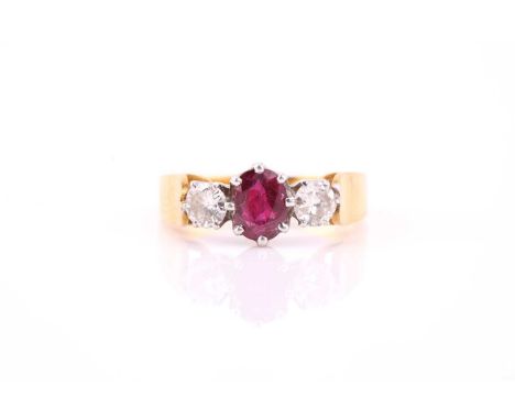 A ruby and diamond three stone half hoop ring; the oval cut ruby in eight claw mount and flanked with round brilliant cut dia