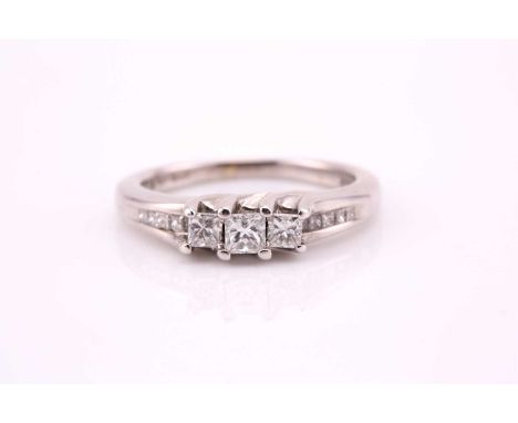 A three stone half hoop daimond ring; the graduated princess cut diamonds in waved claw settings, with five stone princess cu