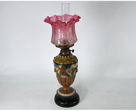 An antique majolica oil lamp, 62 cm h o/all, to/w another oil lamp with cranberry glass reservoir and brass foot - both with 
