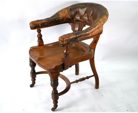 A Victorian mahogany chair with buttoned brown leather yoke back, raised over a crinoline stretcher and on ceramic castors