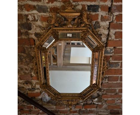 An antique bevel edged cushion framed gilt-wood and composite wall mirror, of octagonal form surmounted by two mermaids flank