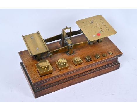 A Victorian set of brass postage scales on wooden plinth, fitted with original square brass graduated weights