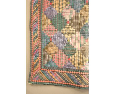 A patchwork quilt showcasing a diamond design in rich, deep shades of forest green, navy and faded red tartan plaid fabrics.
