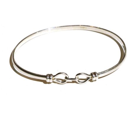 A 9 carat white gold bangle, with a fancy hook fitting, measures 6cm by 5cmGood condition. 9.3g