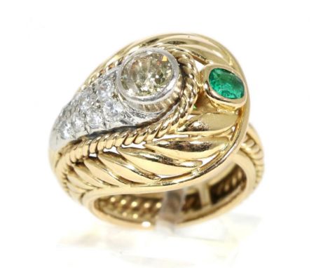 An emerald and diamond crossover ring, an old cut diamond in a rubbed over setting within a pavé set diamond surround, to a f