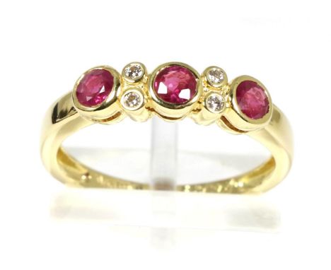 An 18 carat gold ruby and diamond ring, three round cut rubies in rubbed over settings, spaced by pairs of round brilliant cu