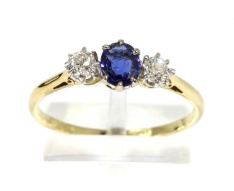 A sapphire and diamond three stone ring, an oval cut sapphire in a claw setting, spaced by old cut diamonds, to knife edge sh