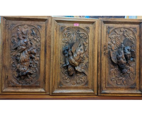 Three finely carved oak panels, one featuring a carving of a hare, the second a bird, lobster and fish, and the third panel o