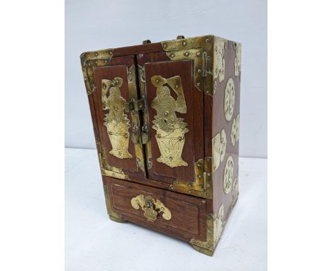 A Chinese wooden and brass mounted desk cabinet, twin doors revealing four internal drawers and one base drawer on bracket fe