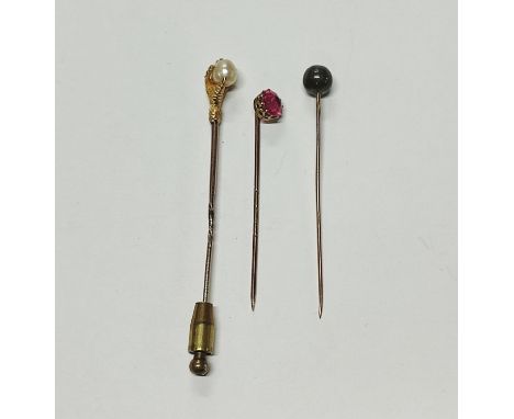 Three unmarked gold metall tie-pins, one a pink sapphire, one a claw surrounding mother of pearl and another (3) 