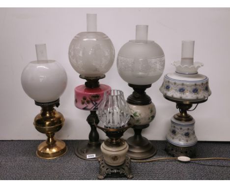 A Victorian pink opaline glass and metal oil lamp together with two further oil lamps and two oil lamp style electric lights.