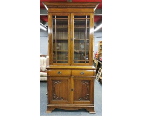 An Art Nouveau carved light oak bookcase over cabinet, H. 235cm, base W. 107cm.