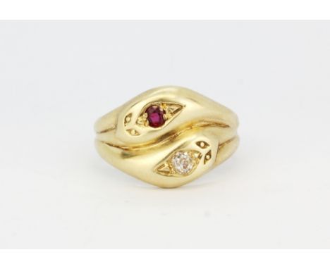 A hallmarked 9ct yellow gold double snake head ring set with a brilliant cut diamond and a round cut ruby, (N).