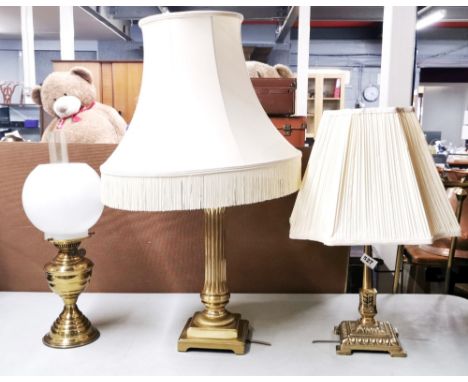 Two brass table lamps and a brass oil lamp, tallest with shade H.76cm.