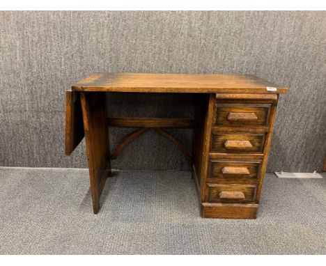 An interesting 1920's dropside oak desk with four drawers and sliding shelf, W. 91cm H. 68cm extended L. 162cm.