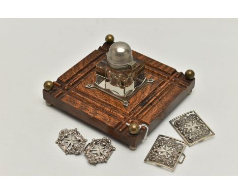 AN INKWELL AND TWO NURSES BELT BUCKLES, a glass and white metal inkwell together with an oak, white metal and brass base, tog