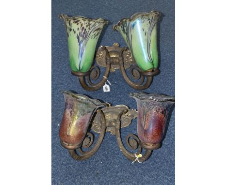 TWO WALL LIGHT FITTINGS WITH IRIDESCENT GLASS LAMP SHADES, the brass light fittings of scrolling, foliate form with acorn fin