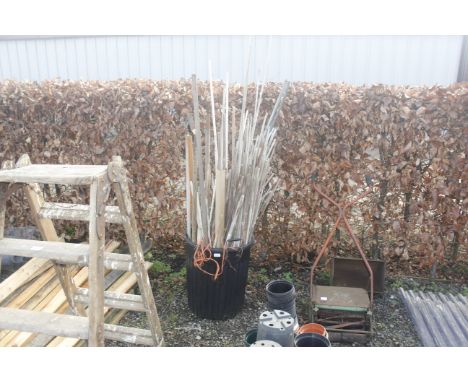 A garden bin containing a large quantity of canes and a small quantity of garden tools