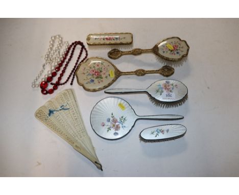 An Adie Brothers Ltd white metal and enamel decorated three piece dressing table set, another dressing table set, a bone fan 