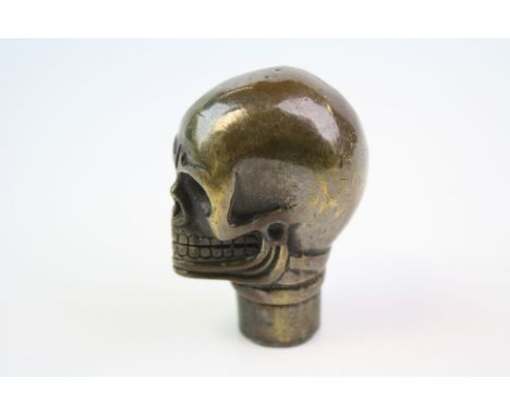 A brass/bronze walking stick handle in the form of a skull.