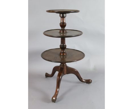 A George II mahogany three tier dumb waiter, with revolving circular tiers and cabriole leg tripod base, fitted brass castors