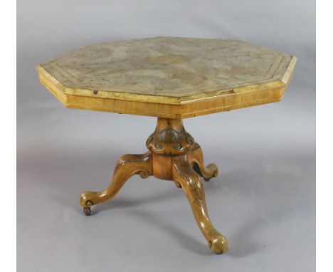 A Victorian burr walnut octagonal centre table, with tilt top and foliate carved tripod base, fitted ceramic castors, W.3ft 3