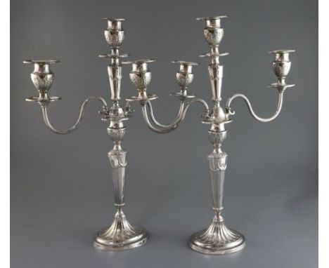 A pair of Edwardian silver two branch three light candelabra by Mappin &amp; Webb, decorated with foliage and swags, on oval 