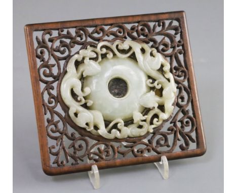 A Chinese archaistic pale celadon jade 'bi' disc, 17th/18th century, the jade of oval form the border carved in openwork with