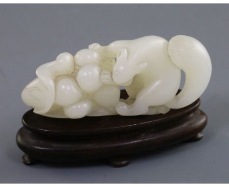 A Chinese white jade carving of a squirrel, grapes and lotus leaf, 18th/19th century, L. 6.4cm, wood stand