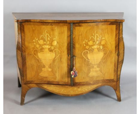 A late 19th century French marquetry inlaid serpentine commode, with two doors, decorated with flowers in urns, enclosing two