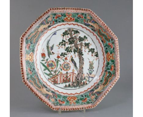 A Chinese famille verte octagonal dish, Kangxi period, painted with two courting birds in a garden with pine tree, flowers an