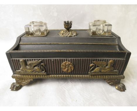 A Regency style ebonized desk ink stand with ormolu taper stick holder, flanked by two glass ink wells, with frieze drawer ha