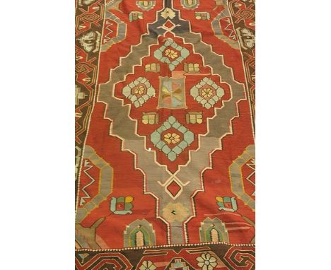 A hand knotted Kelim Persian rug having geometric designs on a red ground with tasselled ends, 109 1/8 x 62