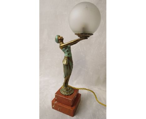 A 1930s cast metal figural table lamp in the form of a gypsy girl with painted highlights, holding a frosted globe shade on a