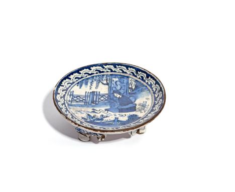 A rare London delftware teapot stand  c.1720, painted in blue with a Chinese figure seated between ornamental fences beneath 