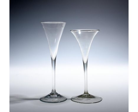 Two toasting glasses  late 17th/18th century, the earlier of a pale green hue, the drawn trumpet bowl with everted rim, both 