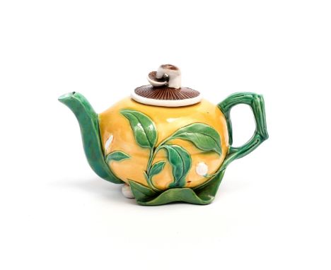 A Minton Majolica teapot and cover  c.1860, the body modelled as a yellow gourd applied with leafy stems, the cover's finial 